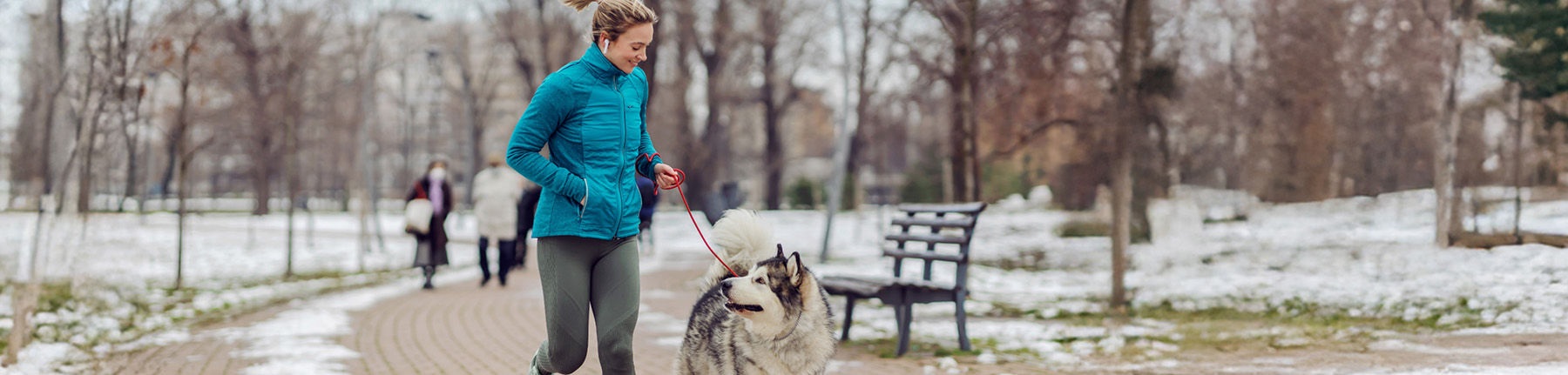 A woman in a black winter jacket with comfortemp® insulation talking on the phone and walking her bicycle.