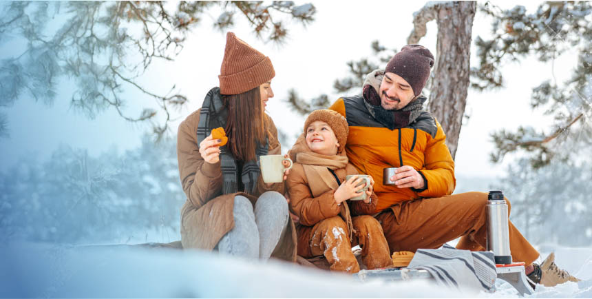 Family enjoying a winter picnic in insulated outerwear, comfortemp® insulation providing warmth in snowy conditions.